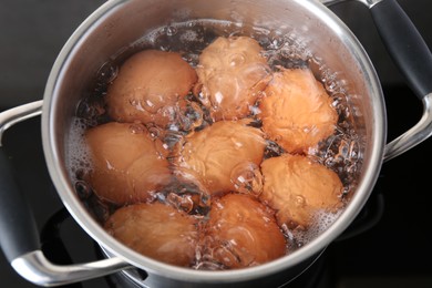 Chicken eggs boiling in pot on electric stove, above view