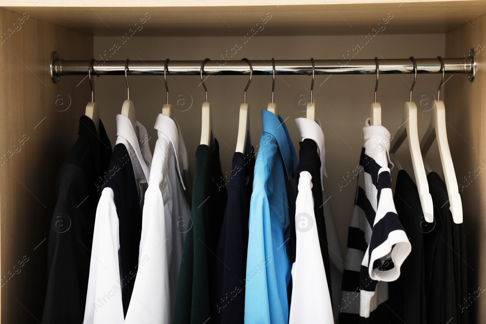 Photo of Hangers with teenage clothes on rack in wardrobe, closeup