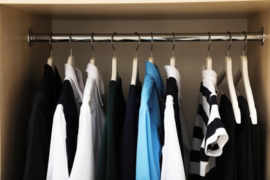 Hangers with teenage clothes on rack in wardrobe, closeup