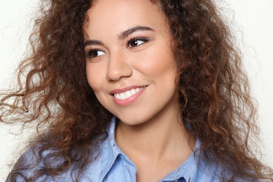 Photo of Young African-American woman with beautiful face on light background, closeup