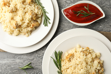 Photo of Delicious chicken risotto served on grey table, flat lay