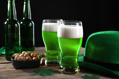 Photo of St. Patrick's day party. Green beer, nuts, leprechaun hat and decorative clover leaves on wooden table