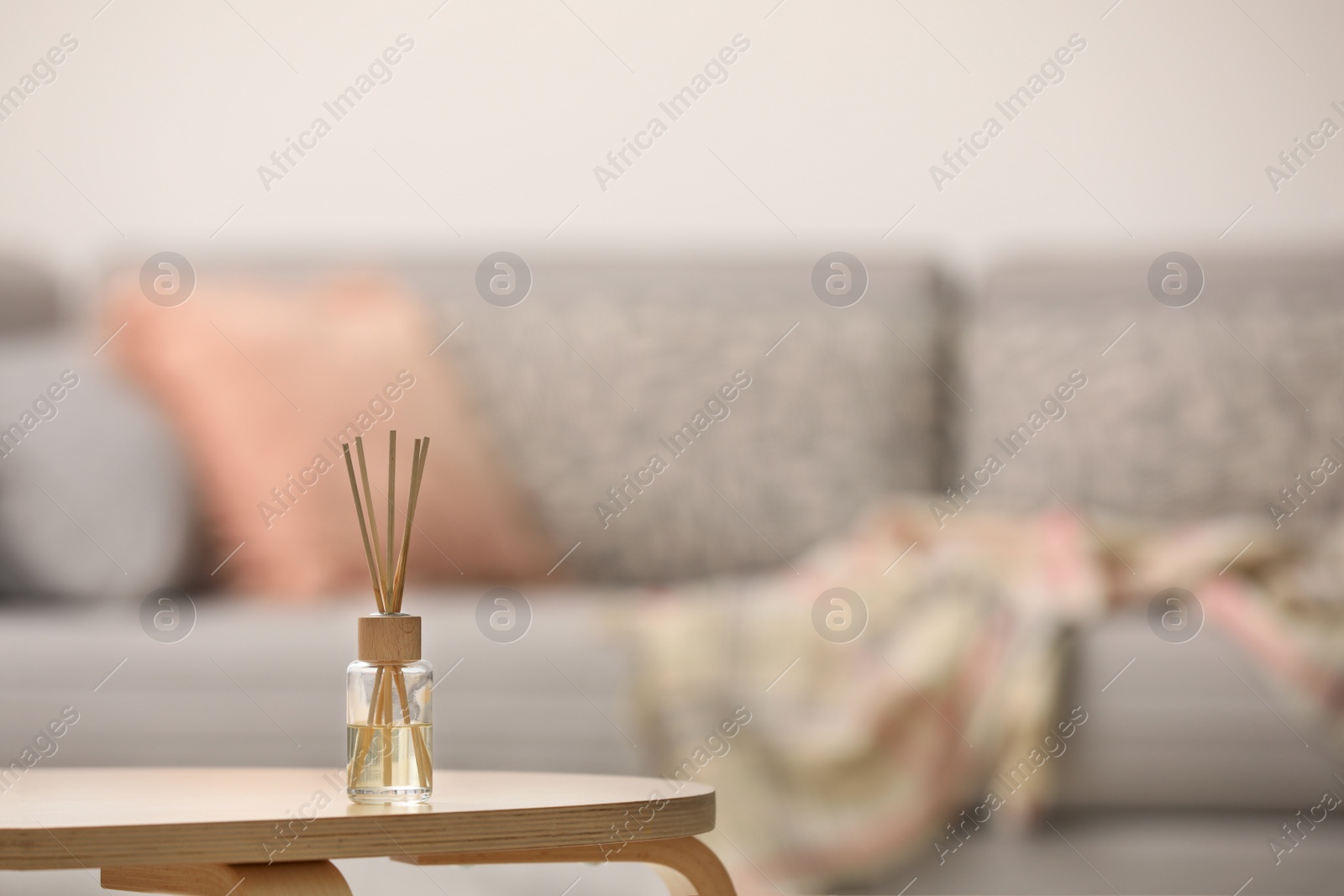 Photo of Reed air freshener with essential oil on table indoors. Space for text