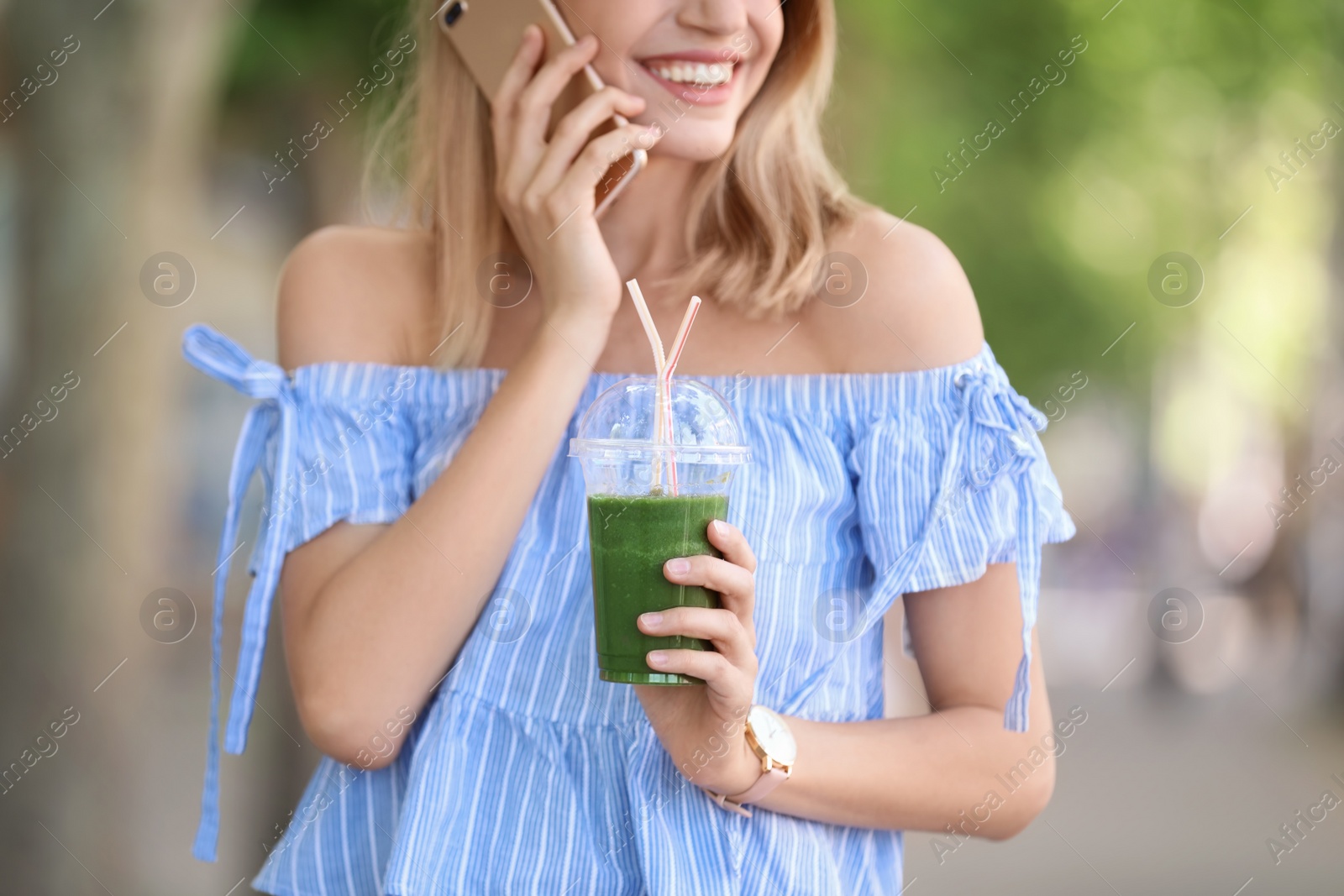 Photo of Young woman with plastic cup of healthy smoothie outdoors