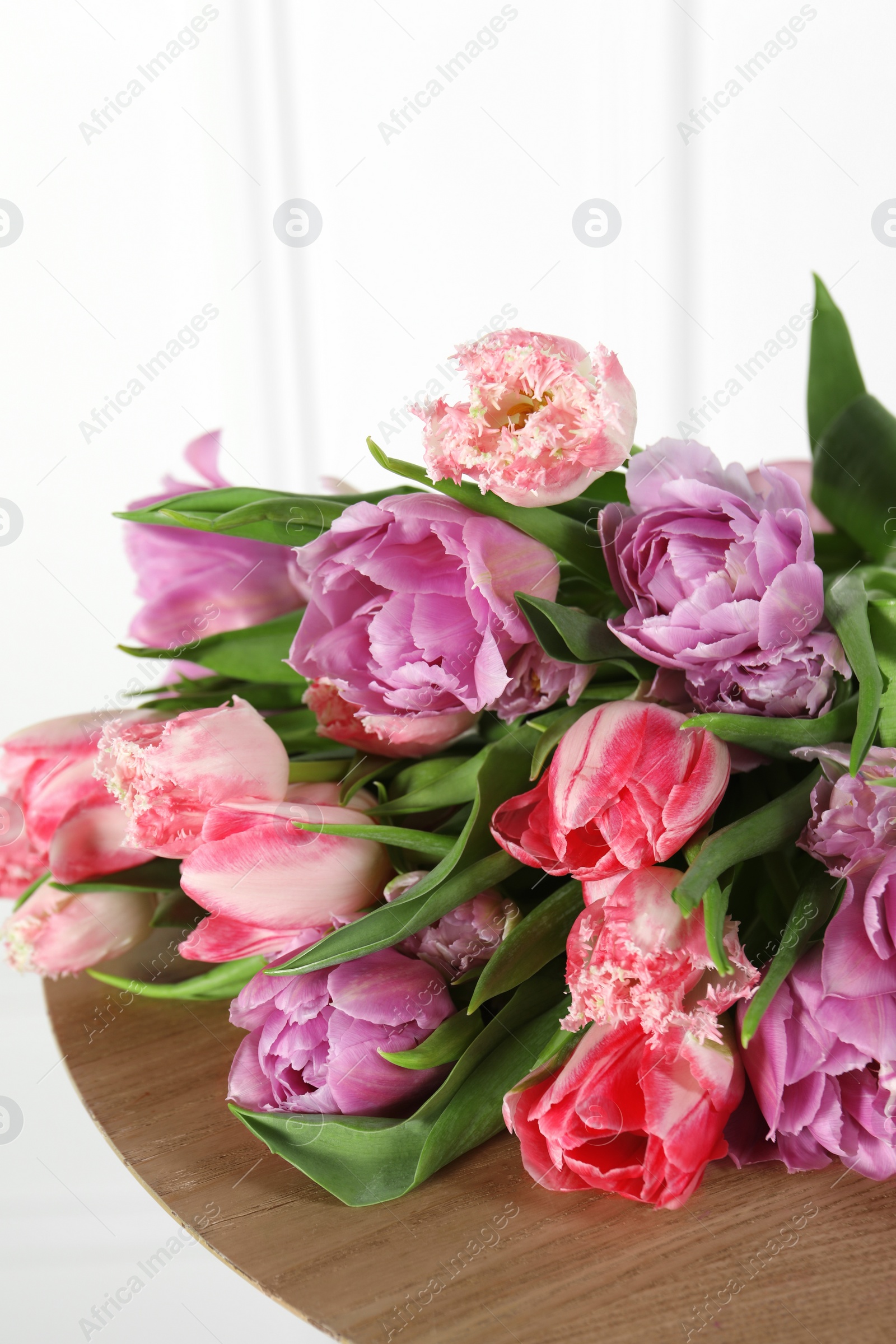 Photo of Beautiful bouquet of colorful tulip flowers on wooden table, closeup