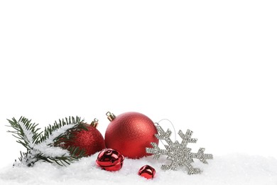 Photo of Beautiful red Christmas balls, fir tree branch and other festive decor on snow against white background