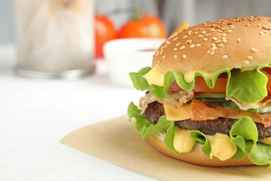 Photo of Tasty burger with bacon on table, closeup. Space for text