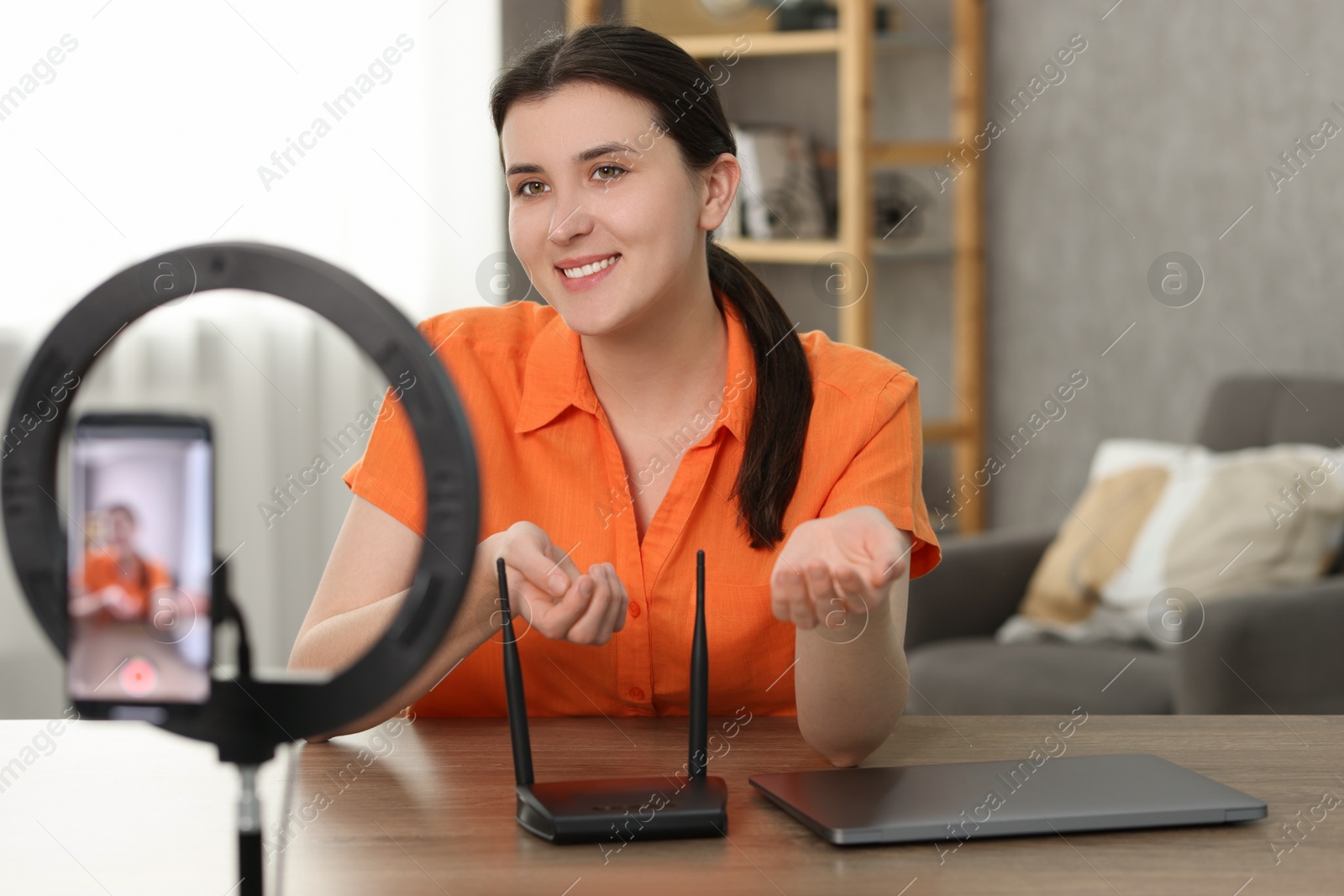 Photo of Smiling technology blogger recording video review about WI-FI router at home