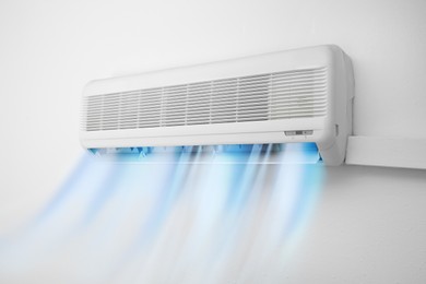 Image of Modern conditioner and illustration of cool air flow on white wall indoors