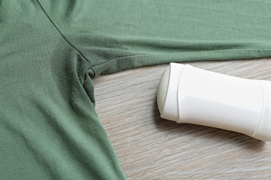 Photo of Clothes with stain and deodorant on wooden background, closeup