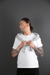 Photo of Young man with stylish tattoos on grey background