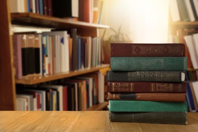 Image of Many stacked hardcover books on wooden table in library, space for text