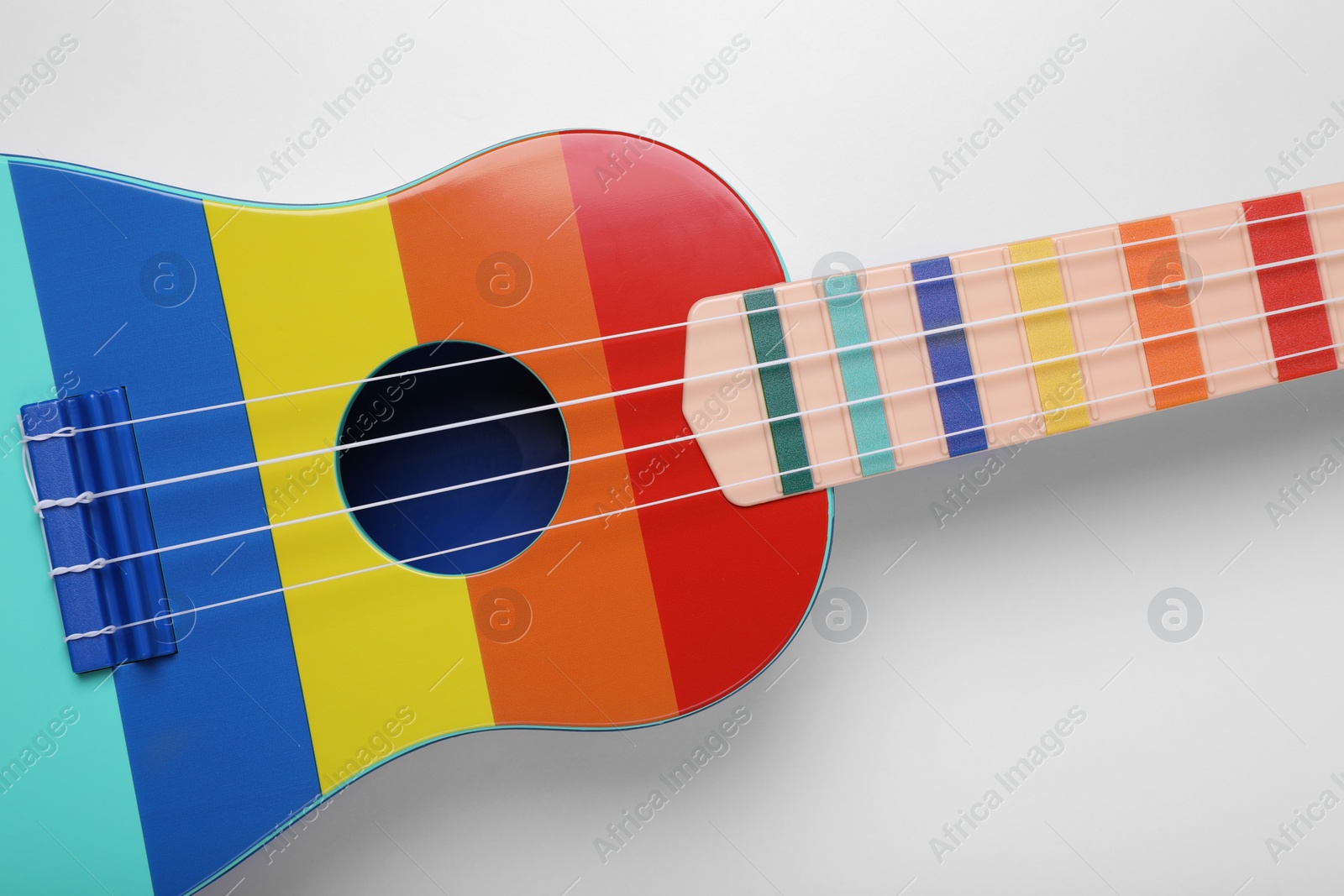 Photo of Colorful ukulele on white background, top view. String musical instrument