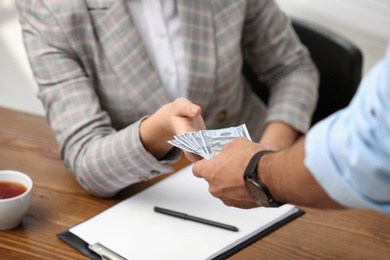 Man giving bribe money to woman at table, closeup