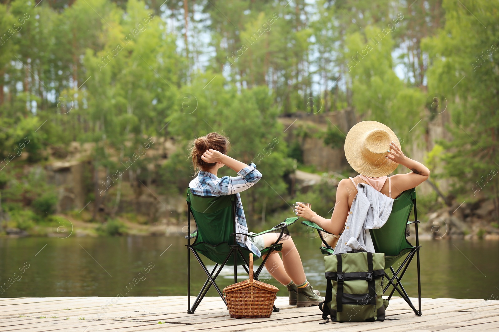 Photo of Young friends resting on pier near lake. Camping season