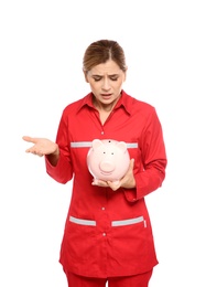 Photo of Portrait of emotional female emergency doctor with piggy bank on white background