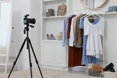 Photo of Fashion blogger's workplace. Shoes, clothes, camera and stylish furniture indoors