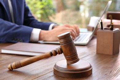 Photo of Gavel and blurred lawyer working with laptop on background