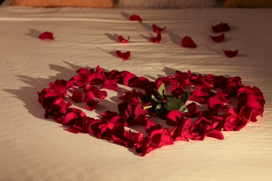 Photo of Honeymoon. Heart made with rose and beautiful petals on bed