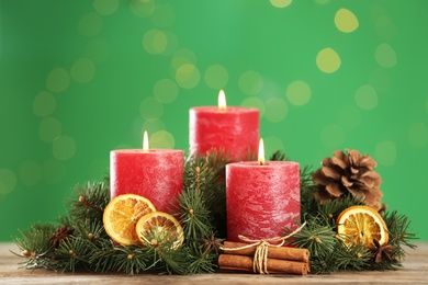 Photo of Beautiful Christmas composition with burning candles on table against green background