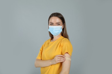 Photo of Vaccinated woman with protective mask and medical plaster on her arm against grey background