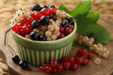 Different fresh ripe currants and green leaf on table, closeup