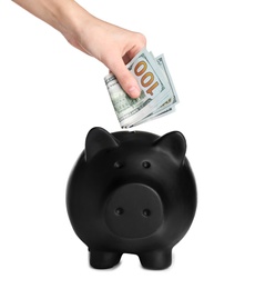 Woman putting money into piggy bank on white background