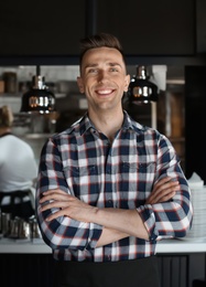 Photo of Portrait of young waiter in uniform at cafe