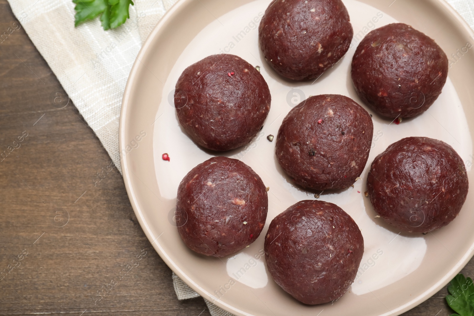 Photo of Many fresh raw meatballs on wooden table, flat lay