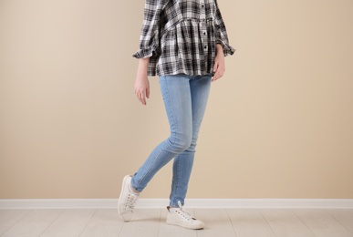 Photo of Young woman in stylish jeans near light wall