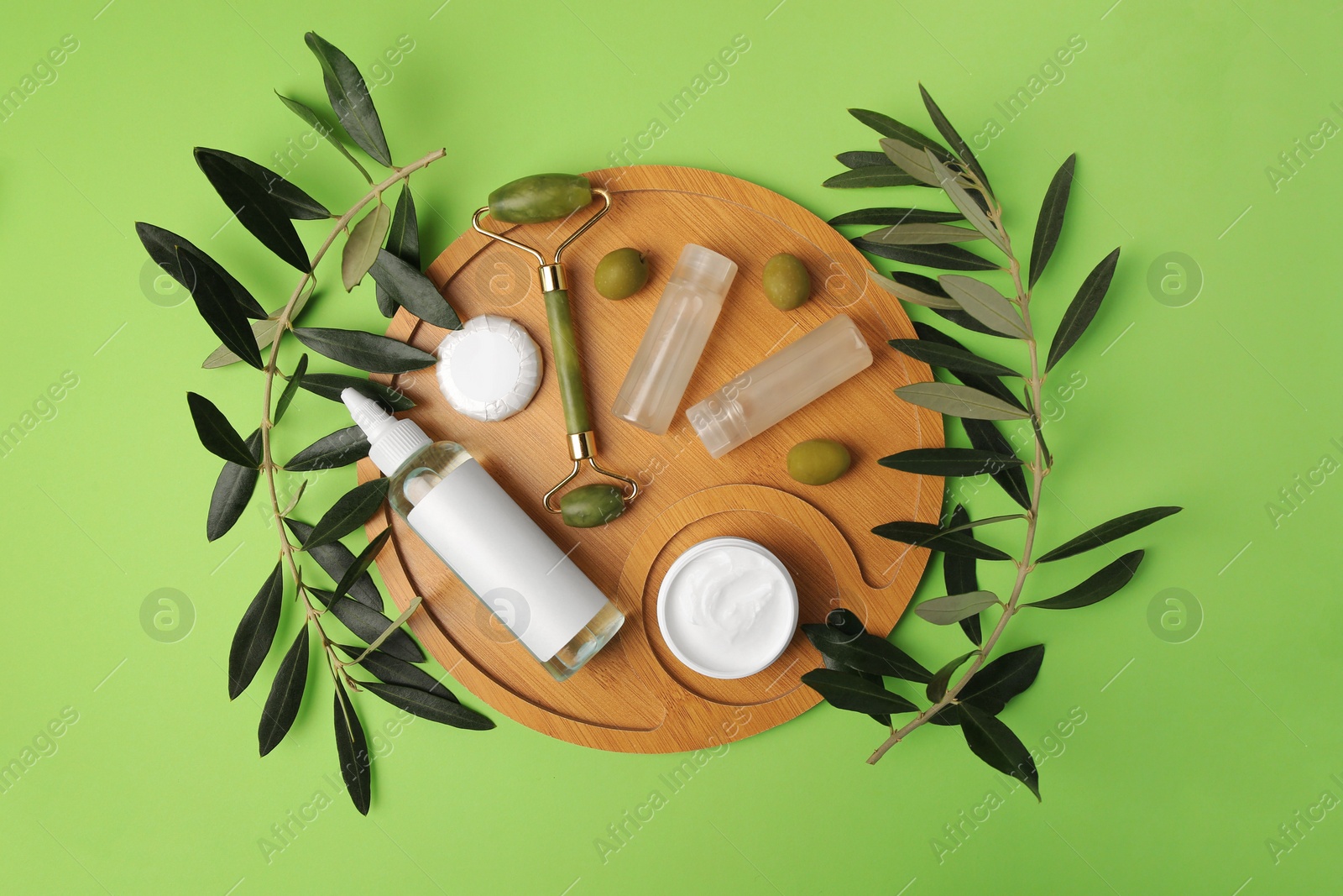 Photo of Different cosmetic products, face roller and olives on light green background, flat lay