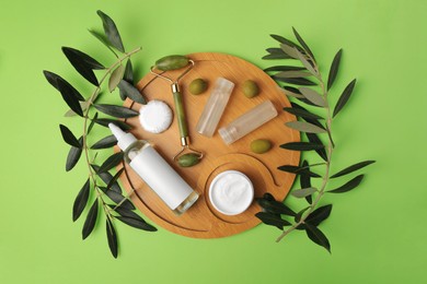 Photo of Different cosmetic products, face roller and olives on light green background, flat lay