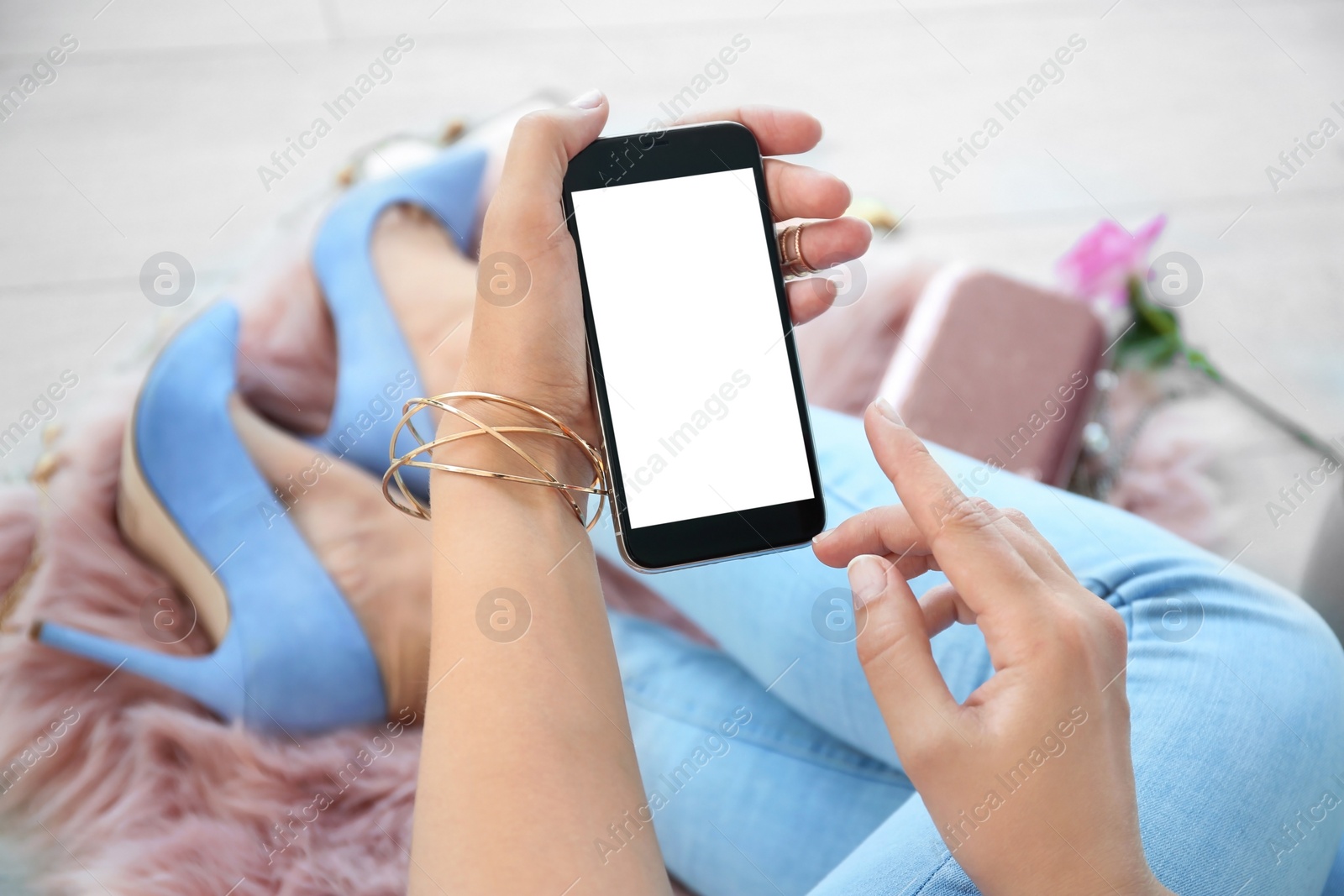 Photo of Young woman holding mobile phone with blank screen in hand, indoors