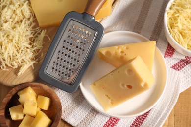 Photo of Grated, cut cheese and grater on wooden table, flat lay