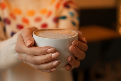 Photo of Woman with cup of aromatic cacao on blurred background, closeup