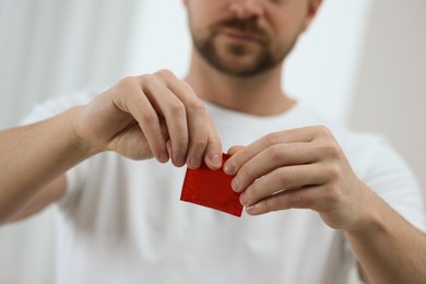 Photo of Closeup view of man opening pack with condom