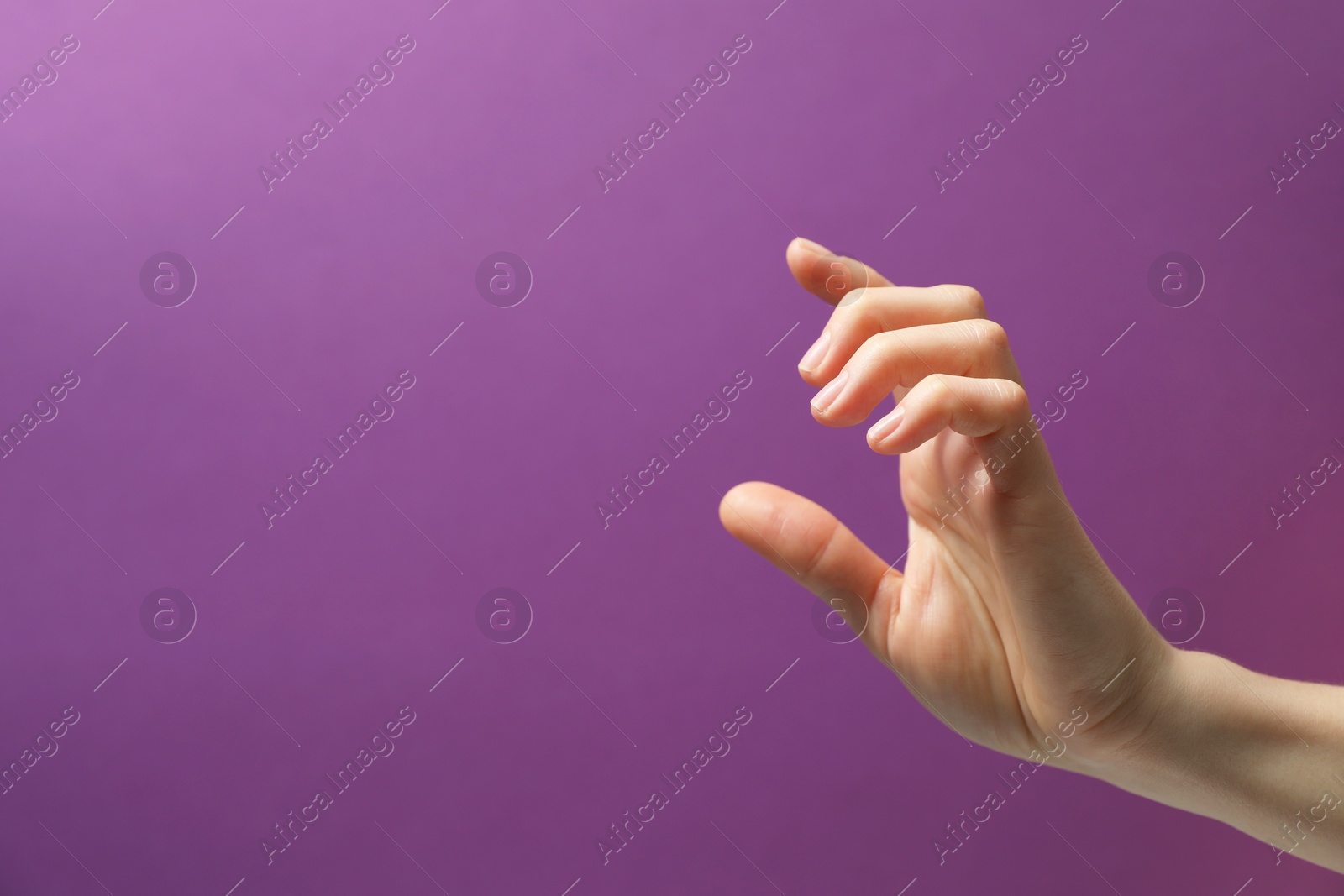 Photo of Woman holding something in hand on purple background, closeup. Space for text