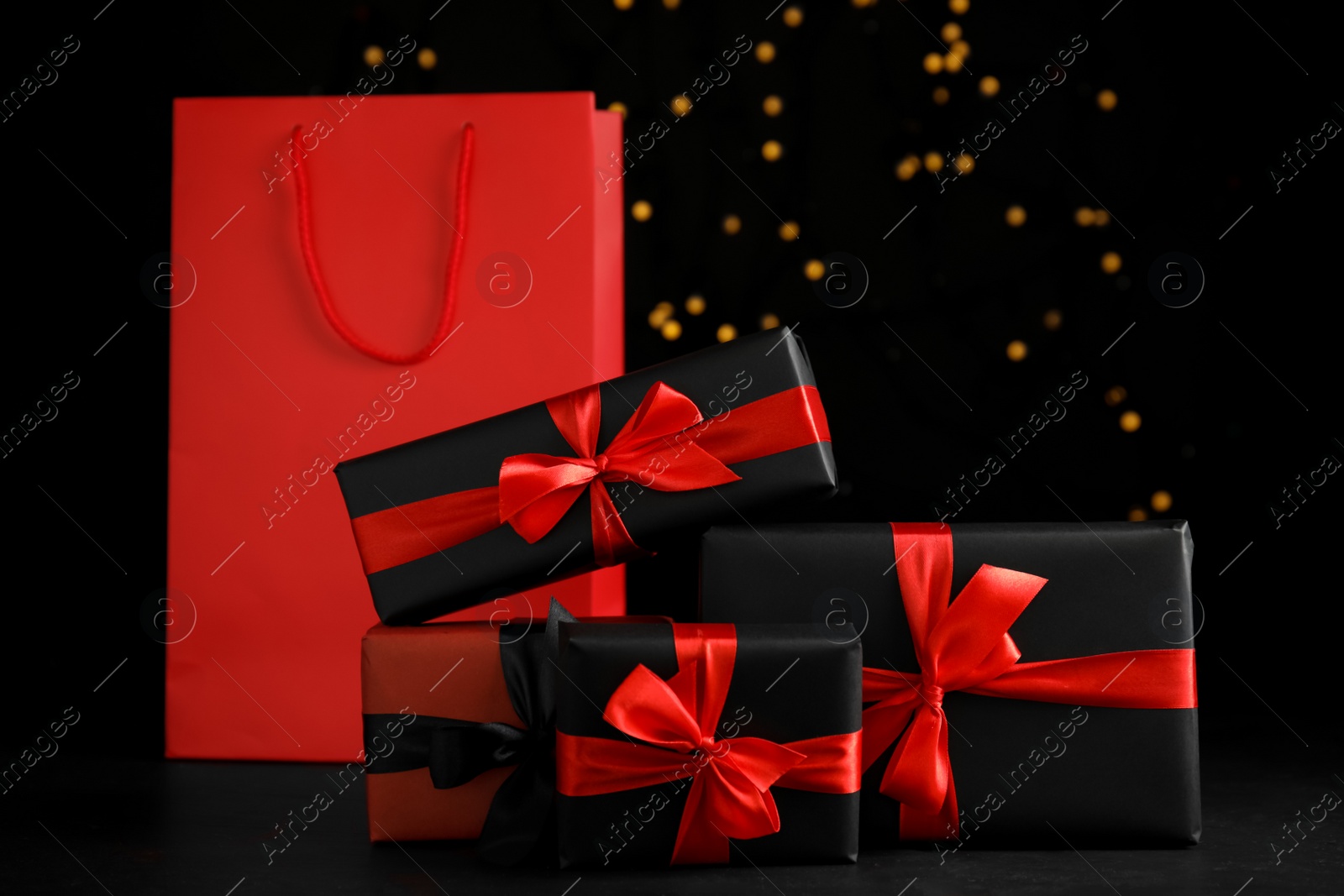 Photo of Gift boxes and paper shopping bag against blurred lights. Black Friday sale