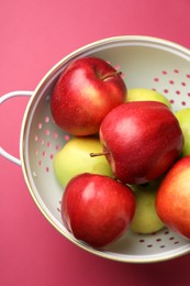 Photo of Colander with fresh apples on pink table, top view