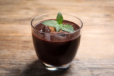 Glass of delicious hot chocolate with fresh mint on wooden table