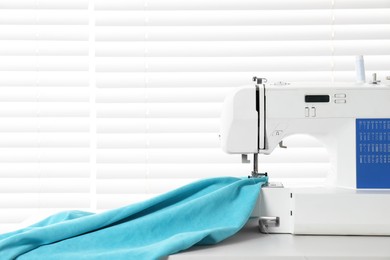 Photo of White sewing machine and fabric on light table indoors