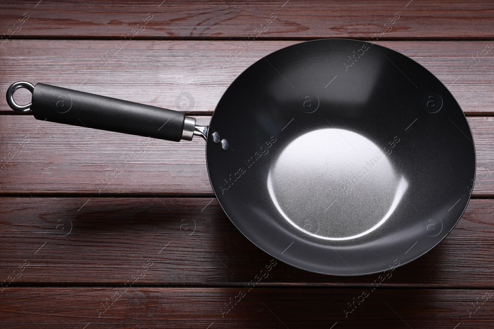 Photo of Empty iron wok on dark wooden table, closeup