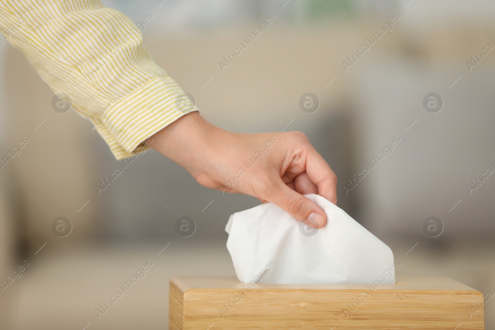 Photo of Woman taking paper tissue from holder indoors, closeup