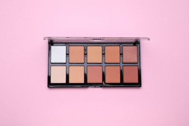 Photo of Contouring palette on pink background, top view. Professional cosmetic product