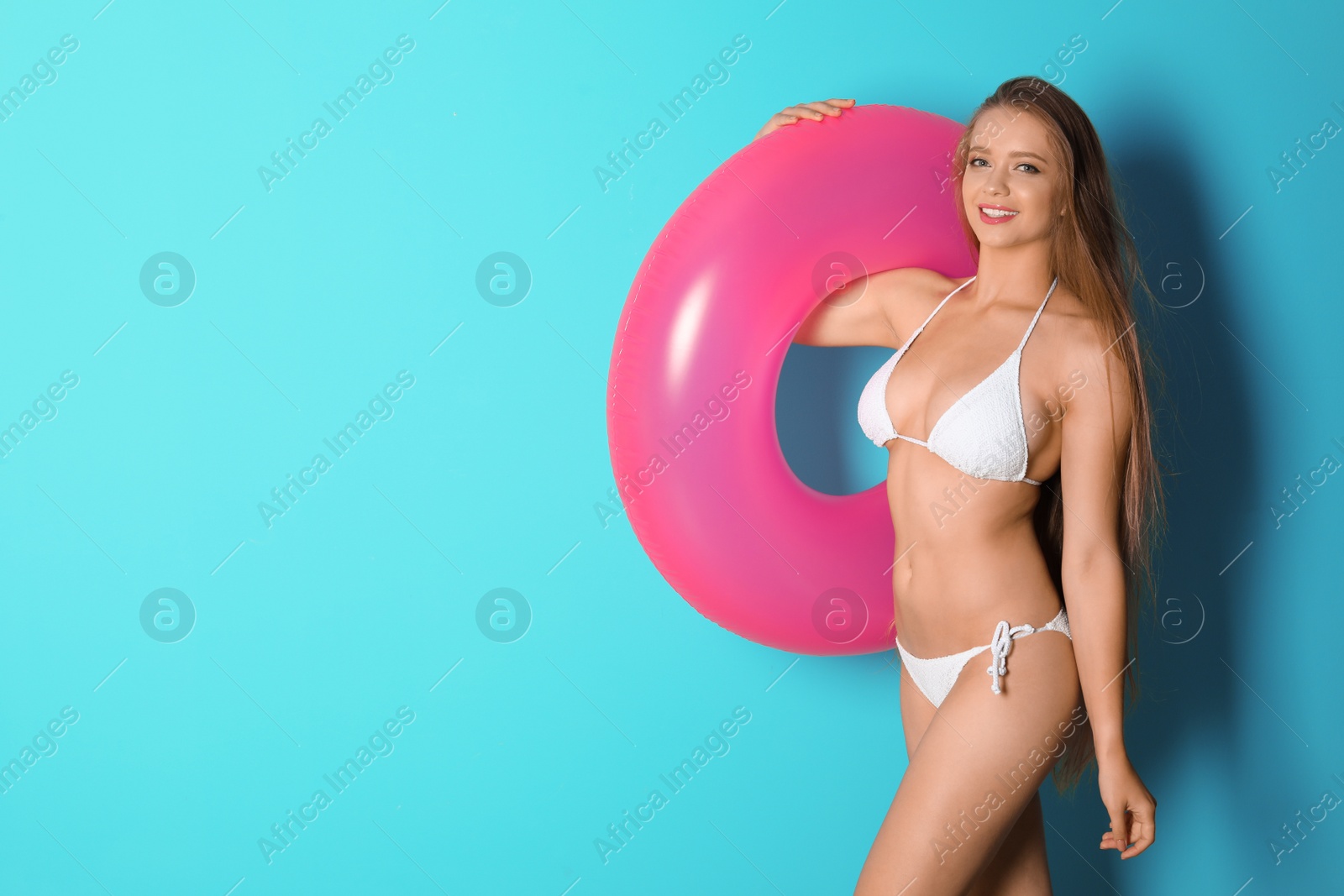 Photo of Beautiful woman with inflatable ring wearing bikini on color background