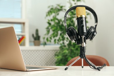 Photo of Microphone, modern headphones and laptop on table indoors