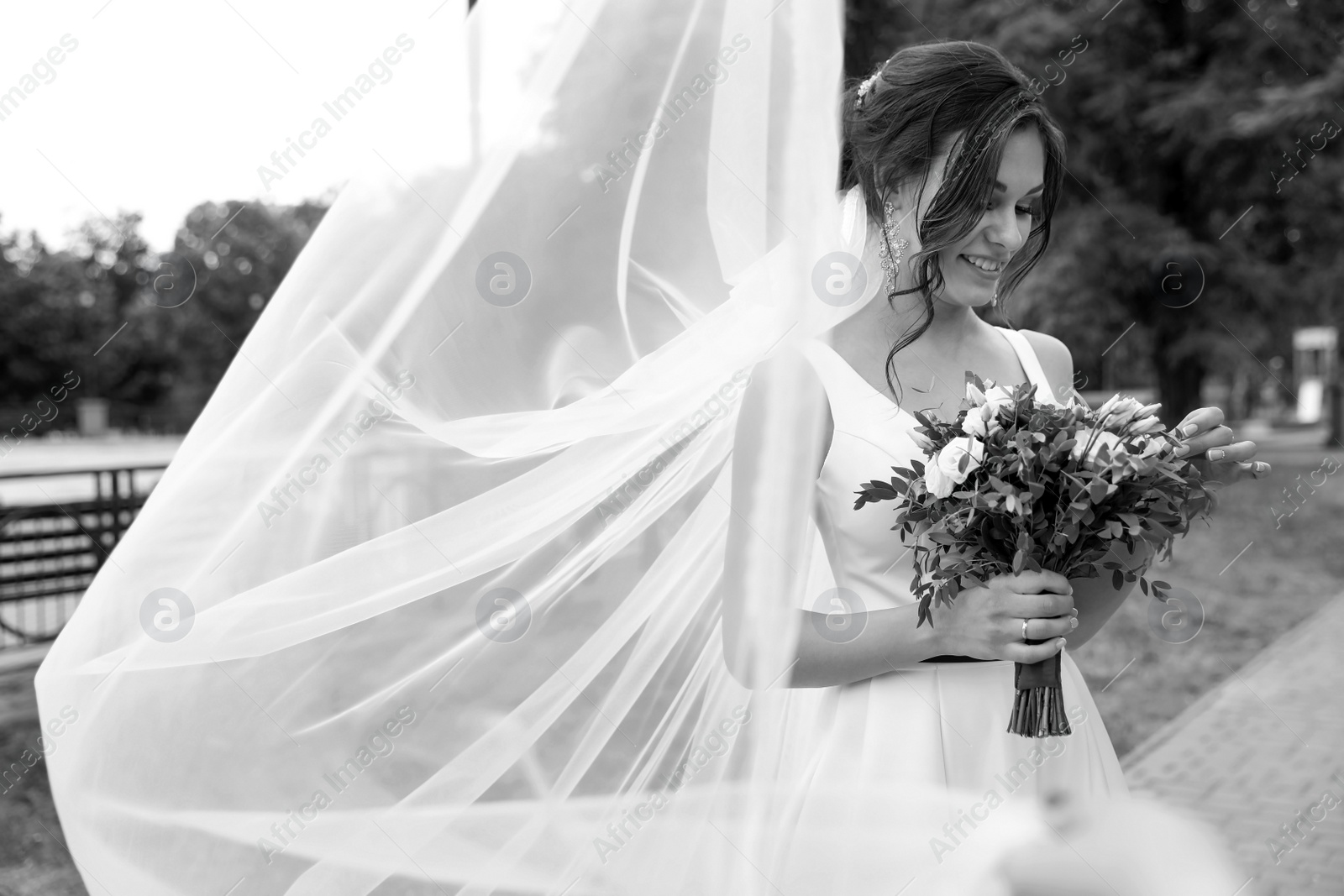 Photo of Young bride with bouquet in long veil outdoors, black and white effect