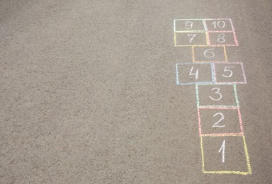 Hopscotch drawn with colorful chalk on asphalt outdoors. Space for text