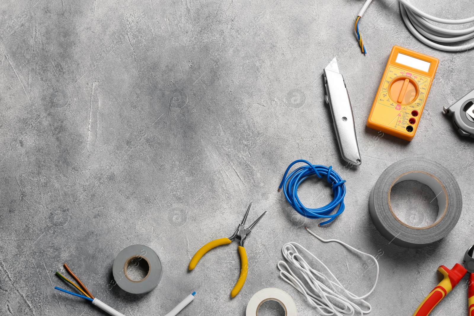 Photo of Wires and electrician's tools on grey table, flat lay. Space for text