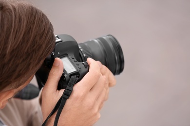 Photo of Male photographer with professional camera on grey background. Space for text